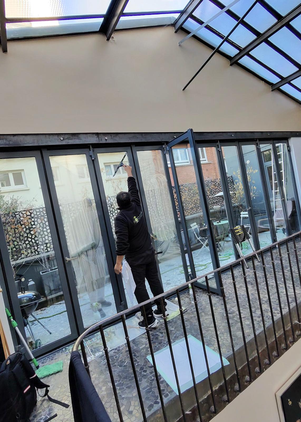 Laveur ISOCLEAN passant la raclette sur une grande baie vitrée sous une verrière