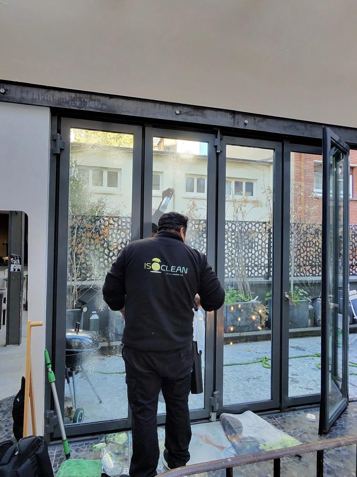 Technicien ISOCLEAN de dos, logo sur la veste, nettoyant une baie vitrée